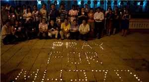 A group of Malaysian residents pose after lighting candles during a vigil for missing Malaysia Airlines passengers at the Independence Square in Kuala Lumpur on March 10, 2014.