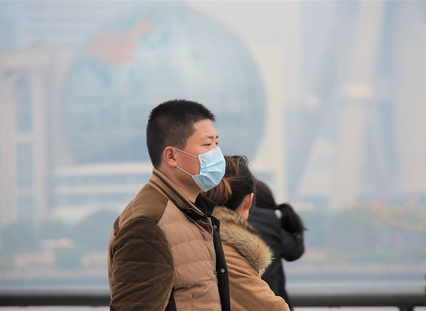 A man on the Bund wears a mask on Monday, as PM2.5 levels rose to more than double the national standard. [By Zhang Suoqing]