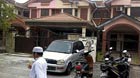 A man walks past the home of co-pilot Fariq Abdul Hamid of the missing Malaysia Airlines Flight MH370. Malaysian police searched the homes of Captain Zaharie Ahmad Shah and the co-pilot of the missing flight on Saturday.