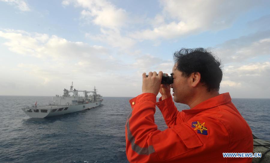 Vice commander of the Chinese rescue vessel 'Nanhaijiu 101' Zhang Jianxin watches as the ship approaching Qiandaohu comprehensive supply ship, as both of them head toward Singapore to join in the search for missing Malaysia Airlines flight MH370, March 18, 2014. At 8:00 a.m. on Tuesday, China's Ministry of Transportation ordered all Chinese vessels in the Gulf of Thailand to leave for searches in the waters southeast of the Bay of Bengal and near the Sunda Strait.