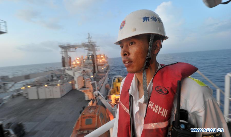 Crew member of the Chinese rescue vessel 'Nanhaijiu 101' Zhao Jun watches as the ship approaching Qiandaohu comprehensive supply ship, as both of them head toward Singapore to join in the search for missing Malaysia Airlines flight MH370, March 18, 2014. At 8:00 a.m. on Tuesday, China's Ministry of Transportation ordered all Chinese vessels in the Gulf of Thailand to leave for searches in the waters southeast of the Bay of Bengal and near the Sunda Strait.