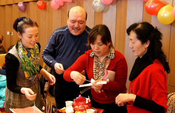Ye Xiaoling (first left) director of the family planning bureau of Weiyang district in Xi’an, and colleagues prepare a birthday party for bereaved parent Xue Mingxin (second left). [Photo/China Daily]