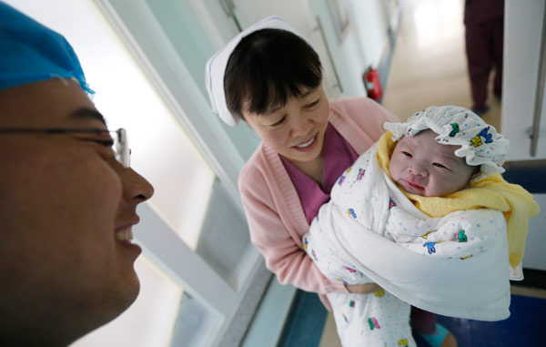 A father admires his newborn at a hospital in Qingdao, Shandong province, on Sunday.[Photo/China Daily]