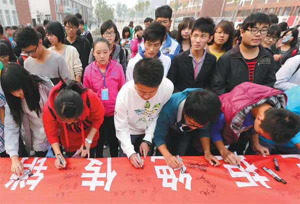 College students sign their names on a banner promising not to participate in pyramid schemes in Huaibei, Anhui province, in March 2013. Students make up more than 70 percent of the members of pyramid schemes. [Photo/China Daily] 