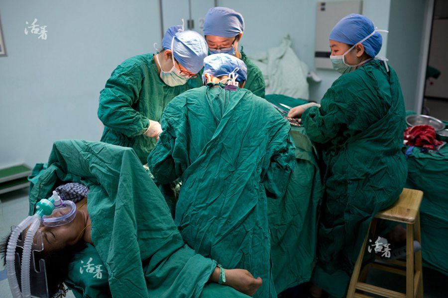 Obstetricians sew up the wound after Xing Li gives birth to a pair of twin boys via C-section on the morning of April 25. [Photo/qq.com]