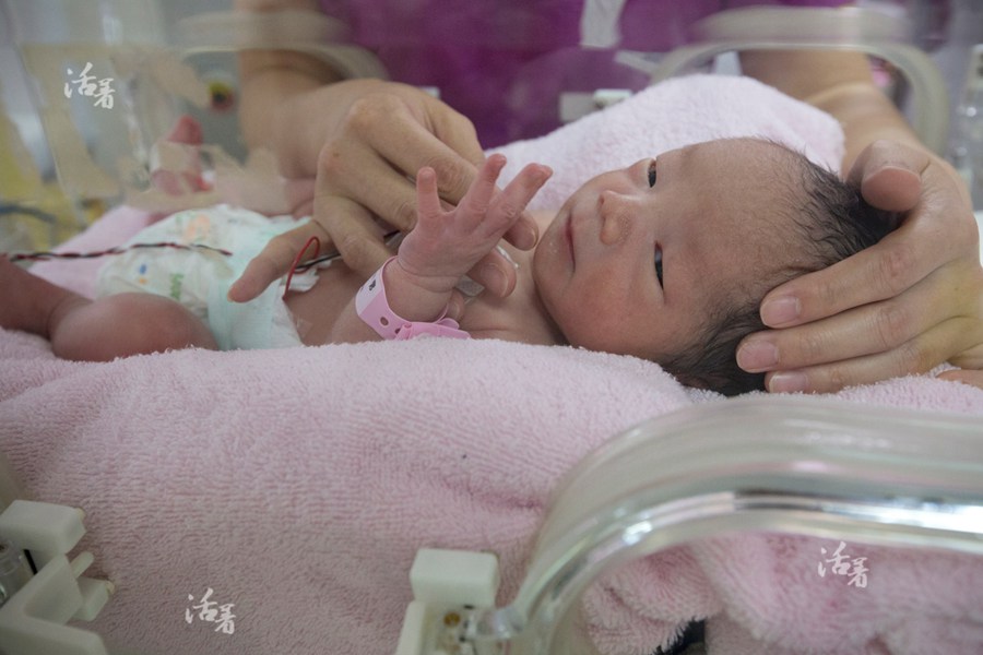 The younger of the two premature babies opens his eyes to look around in an incubator at an intensive care unit at the hospital. [Photo/qq.com] 
