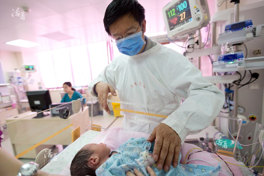 Xing Li&apos;s husband smiles as he touches his older son at an intensive care unit at a hospital in Beijing. The son still could not open his eyes. [Photo/qq.com] 