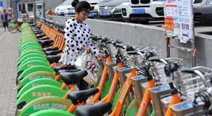 A woman takes a bicycle at a public bike rental station in Taiyuan, capital of north China's Shanxi province, May 25, 2014. A city-wide bike sharing system has operated in Taiyuan since 2012. A total of 1120 rental stations with 35,000 bicycles are involved in this program by now.