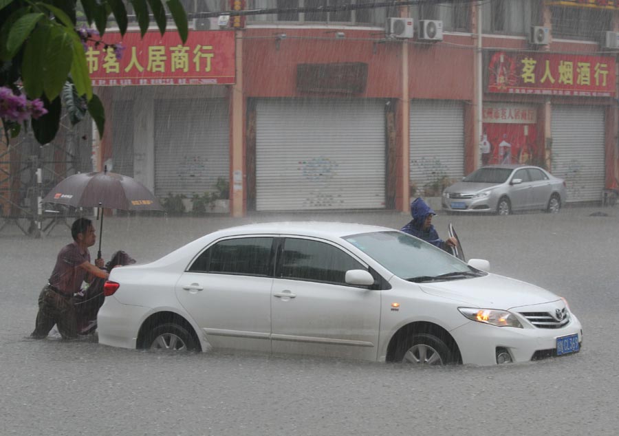 People help to push a stalled car out of pooled water as heavy rainfall strikes Qinzhou, a city in southern part of southern China's Guangxi Zhuang autonomous region on Wednesday. [Photo/Xinhua] 