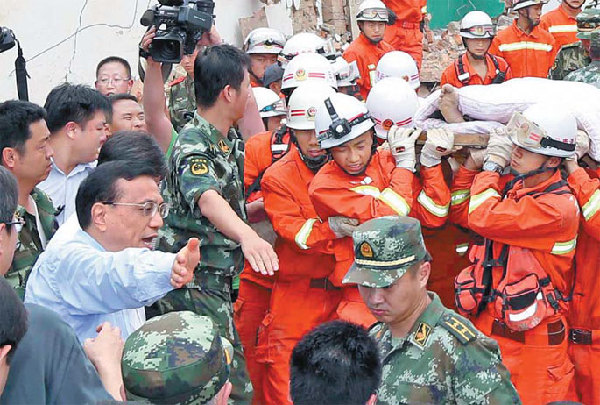 Premier Li Keqiang helps make way for rescuers carrying victims on Monday while inspecting the township of Longtoushan, epicenter of Sunday's earthquake in Yunnan province. [Photo/Xinhua]