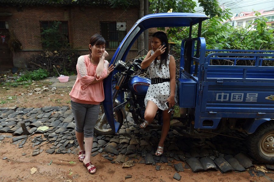 Vietnamese bride Nguyen Thi Hang (left) and fellow Vietnamese bride Vu Thi Hong Thuy share a moment in a yard behind the shop where Hang works in Weijian Village, in central China’s Henan Province. More than 20 Vietnamese brides have found new lives in the poverty-stricken rural township.