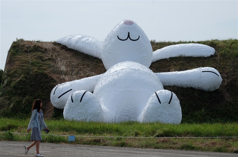  A woman in Taoyuan walks past a giant rabbit created by Dutch artist Florentijn Hofman.