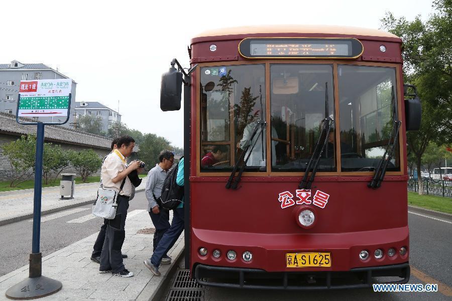 Tourists take the pseudo-classical sightseeing bus powered by pure electricity in Beijing, capital of China, Sept. 28, 2014. [Photo: Xinhua]