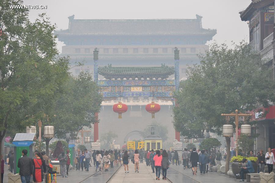 Tourists visit the Qianmen Street in smog-shrouded Beijing, capital of China, Oct. 9, 2014.