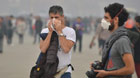 A foreign tourist (L) adjusts his mask as visiting the smog-shrouded Tian'anmen Square in Beijing, capital of China, Oct. 9, 2014.
