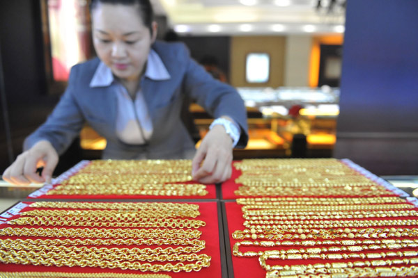 A saleswoman sorts gold products at a shop in Lin'an, Zhejiang province. Chinese consumers bought 182.7 metric tons of jewelry, gold bars and coins for investment in the third quarter, a 37 percent year-on-year decline. [Photo/China Daily]