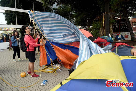 A protester dismantles a tent outside the Citic Tower in Admiralty, Hong Kong on Nov 18, 2014. [Photo/China News Service]    
