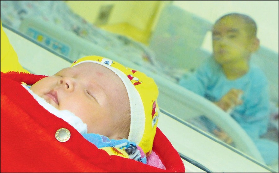 Tongtong sleeps in her mother's arms, while nearby her brother An'an, 3, awaits yesterday's stem cell transplant from his baby sister. — Wang Rongjiang 