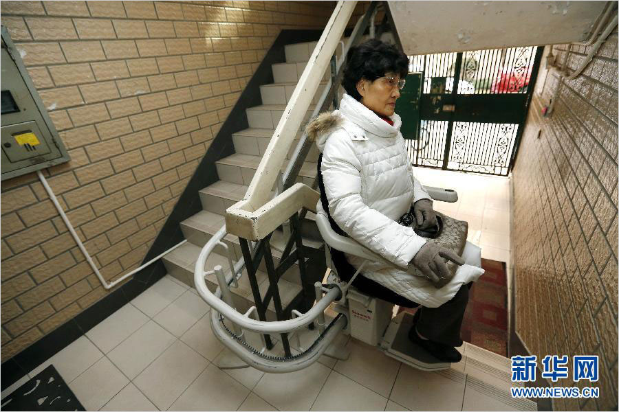 Wang Qian uses the stairlift installed at her residential building in Jing'an District in Shanghai on December 17, 2014. [Photo: Xinhua]