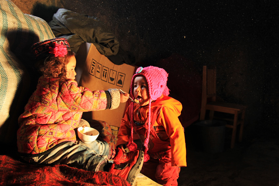 Gulaxiami feeds her younger sister at home, Nov 24, 2014. [Photo by Wang Lie/chinadaily.com.cn] 