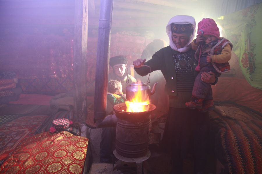 Gulaxiami (left) plays with her father, while her mother places a kettle on a fire with her yonger sister in the arm in the morning. [Photo by Wang Lie/chinadaily.com.cn] 