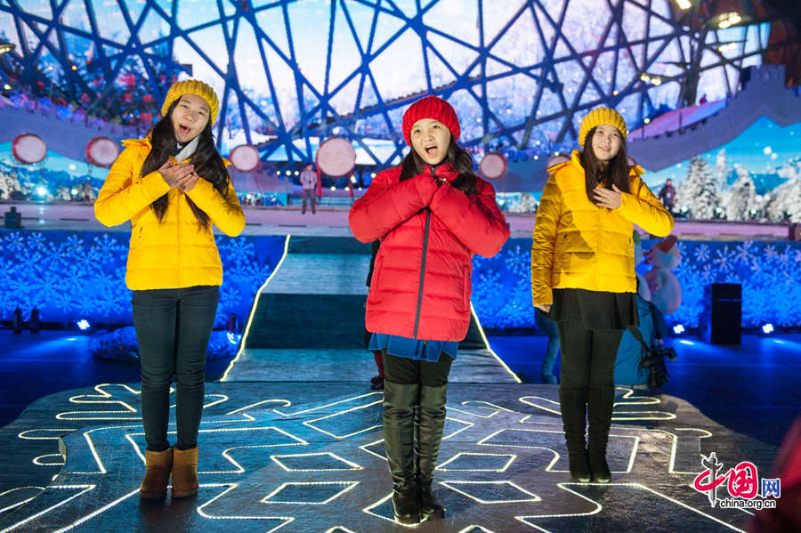 Lin Miaoke (M) and her friends sing at the rehearsal of Countdown to 2015, the New Year celebration, on Dec. 30, one day ahead of the actual ceremony. The New Year celebration 'Countdown to 2015' holds its last rehearsal at Beijing's Olympic Park, where the national symbols of the Bird's Nest stadium and the Water Cube National Aquatics Center are located, on Tuesday, Dec. 30, 2014. The ceremony also features the Chinese capital's bidding for the 2022 Winter Olympics. [Photo by Chen Boyuan / China.org.cn]