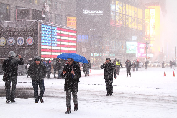 People walk in the snow at the Time Square in New York city Monday. Hu Haidan / China Daily 