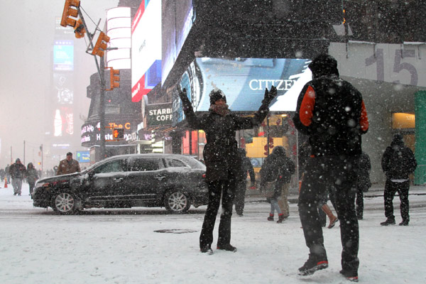 People take pictures in the falling snow in Time Square in New York city Monday. Hu Haidan / China Daily 