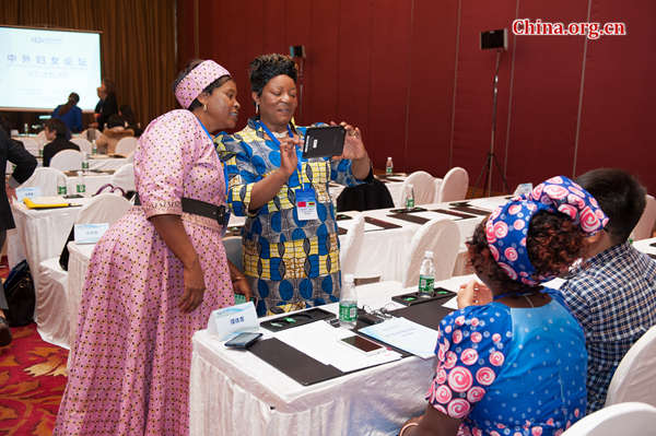 Women representatives from Zimbabwe take photos with their Chinese Lenovo mobile phone during a tea break at the International Forum on Women held in Beijing on Oct. 14, 2015. [Photo by Chen Boyuan / China.org.cn]