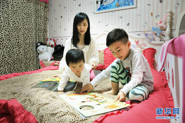 Ye Hua, mother of two children, tells a bedtime story to her children in Shanghai, China, May 4, 2016. [Photo: Xinhua]