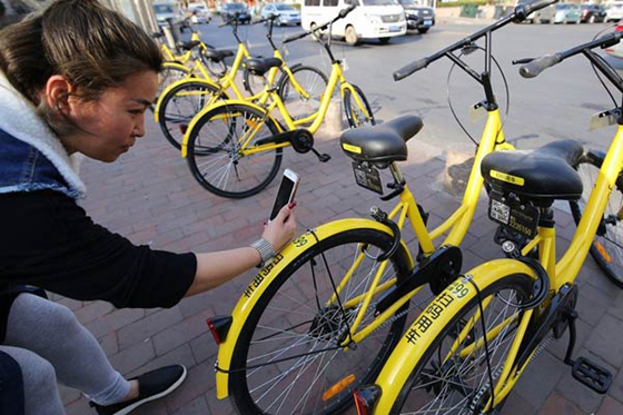 A rider in Qingdao, Shandong province, scans bar code for riding an ofo bike. [Photo/China Daily] 