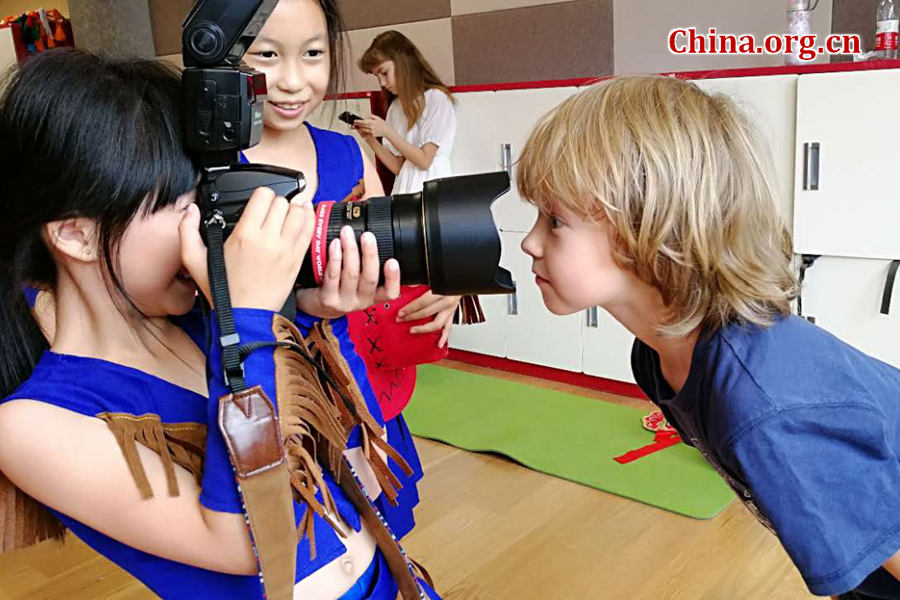 International children have fun with the photographer's professional camera on May 30 during a rehearsal for a performance scheduled on the next day as part of the celebration activities for the International Children's Day. [Photo by Chen Boyuan / China.org.cn]
