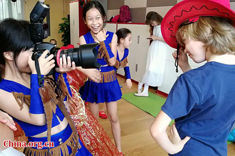 International children have fun with the photographer's professional camera on May 30 during a rehearsal for a performance scheduled on the next day as part of the celebration activities for the International Children's Day. [Photo by Chen Boyuan / China.org.cn]