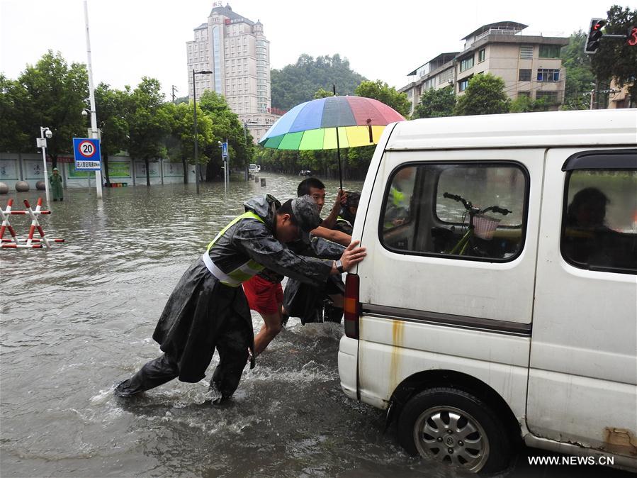 People move a car on a flooded street in Guiyang City, capital of southwest China's Guizhou Province, June 12, 2017. Heavy rain hit Guizhou since Sunday.(Xinhua/Zhang Hui) 