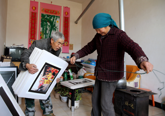 Xie Wanqing prepares display panels with the help of his wife An Guiqin at home on Jan. 5, 2017. [Huo Yan/for China.org.cn] 