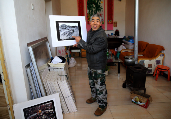 Xie Wanqing shows his photographs works and tells the stories behind them at home on Jan. 5, 2017. [Huo Yan/for China.org.cn]